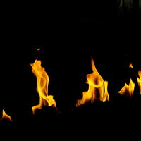 黒い背景に燃えつづけるオレンジと黄色の炎の写真