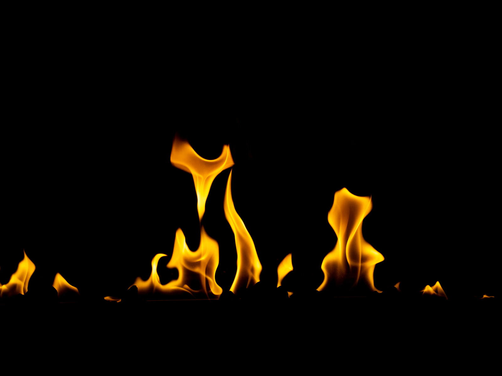 黒い背景から立ち上がるオレンジ色の炎が複数燃え上がっている