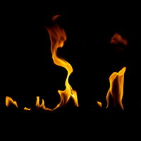 黒い背景で炎がメラメラと揺れながら燃える様子の写真