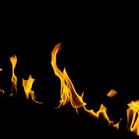 黒背景に燃え上がるオレンジ色の炎の写真の写真