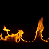 黒い背景に揺らめくオレンジ色の炎が燃え上がる風景の写真