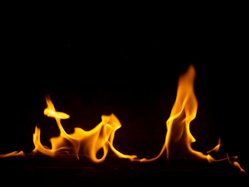 黒い背景に揺らめくオレンジ色の炎が燃え上がる風景
