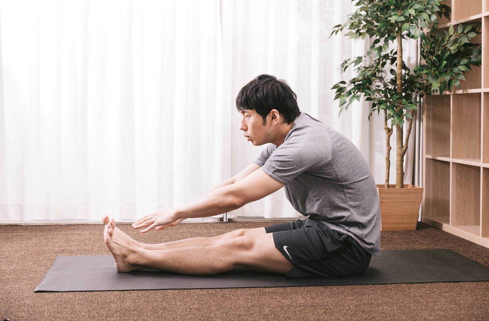 ヨガマットの上で前屈ストレッチをする体の硬い男性［モデル：大川竜弥］