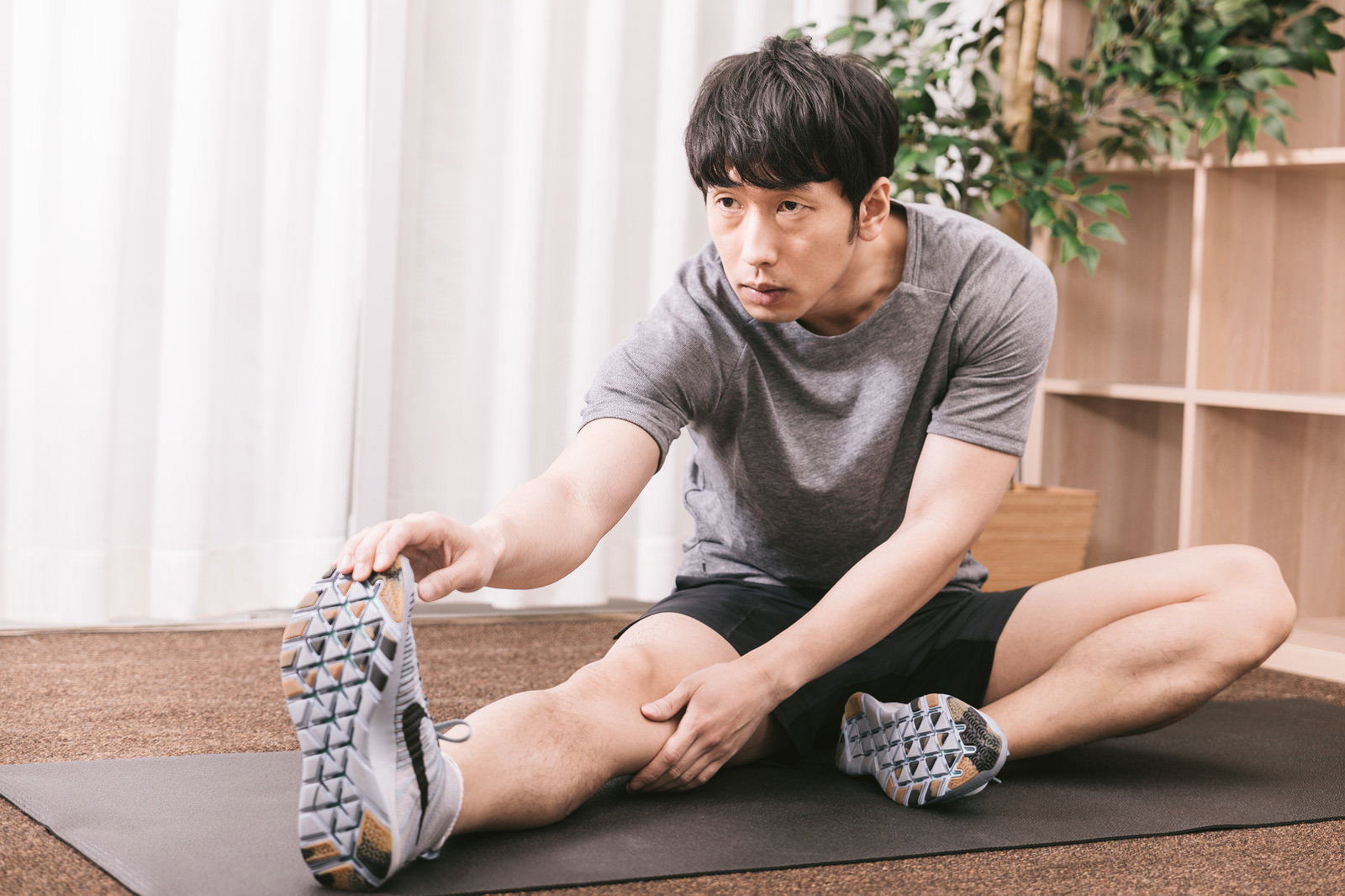 ヨガマットの上でストレッチをする男性トレーニー［モデル：大川竜弥］