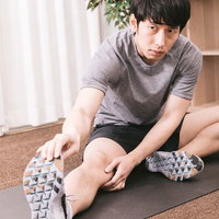 ヨガマットの上で入念に準備運動をするスポーツマンの写真