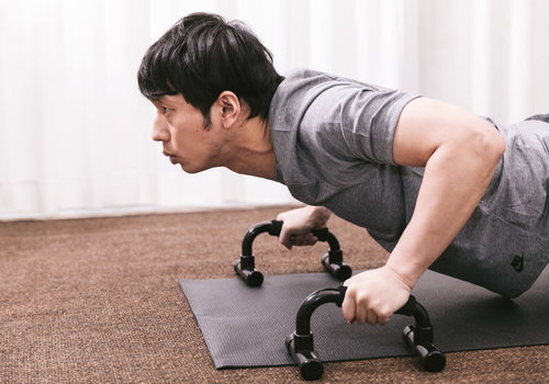 プッシュアップバーで大胸筋を鍛える男性のトレーニング