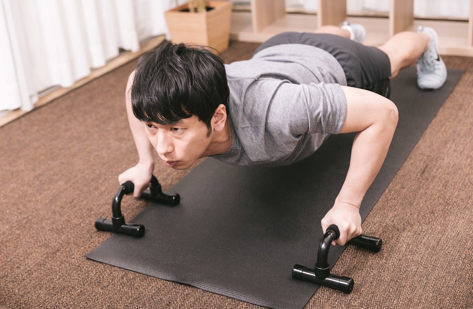 プッシュアップバーを使って腕立て伏せをする男性［モデル：大川竜弥］