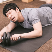 バランスボールに座ってスマホを操作する男性の写真