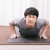 疲労物質が溜まり苦痛に顔を歪める男性のトレーニング姿の写真