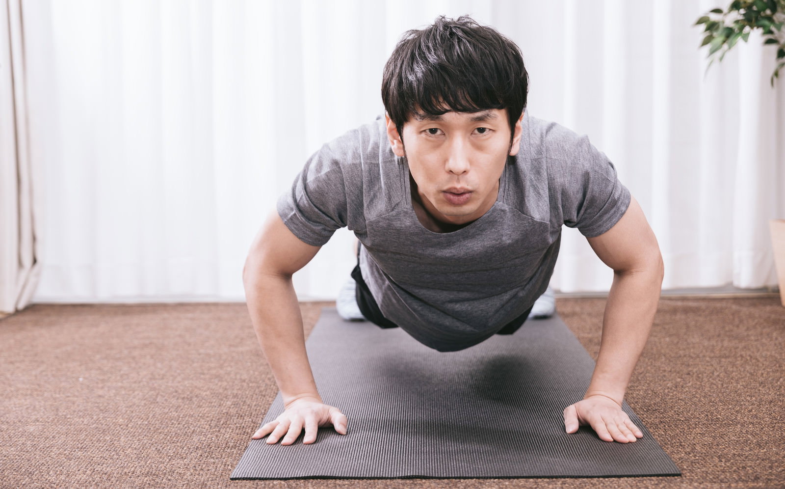 室内のマットで腕立て伏せをするグレーのシャツを着た男性［モデル：大川竜弥］