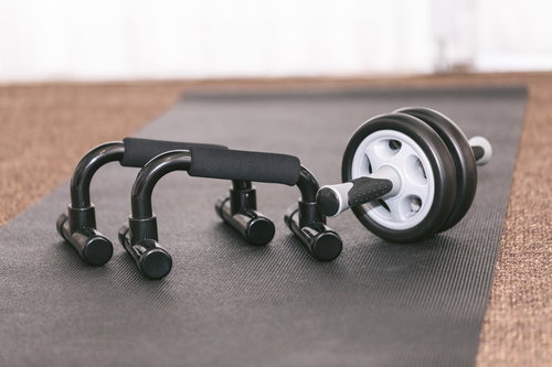 黒いプッシュアップバーと白い腹筋ローラーを並べたトレーニング器具