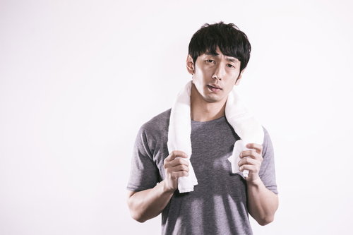 タオルが部屋干し臭い男性の汗を拭く姿、運動後の疲労