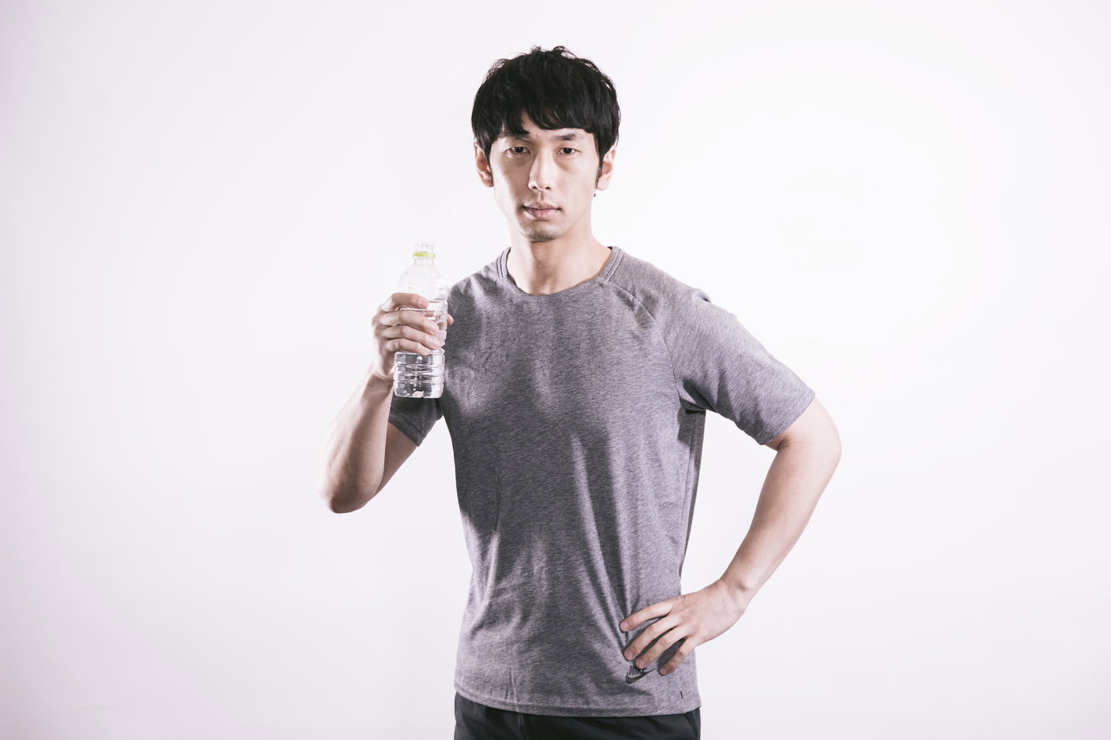 グレーのTシャツを着てスポーツドリンクを飲む男性［モデル：大川竜弥］