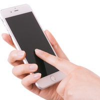 スマホの画面をタップする女性の手の写真