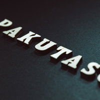 暗いグラデーション背景に浮かぶPAKUTASOの白い立体文字の写真