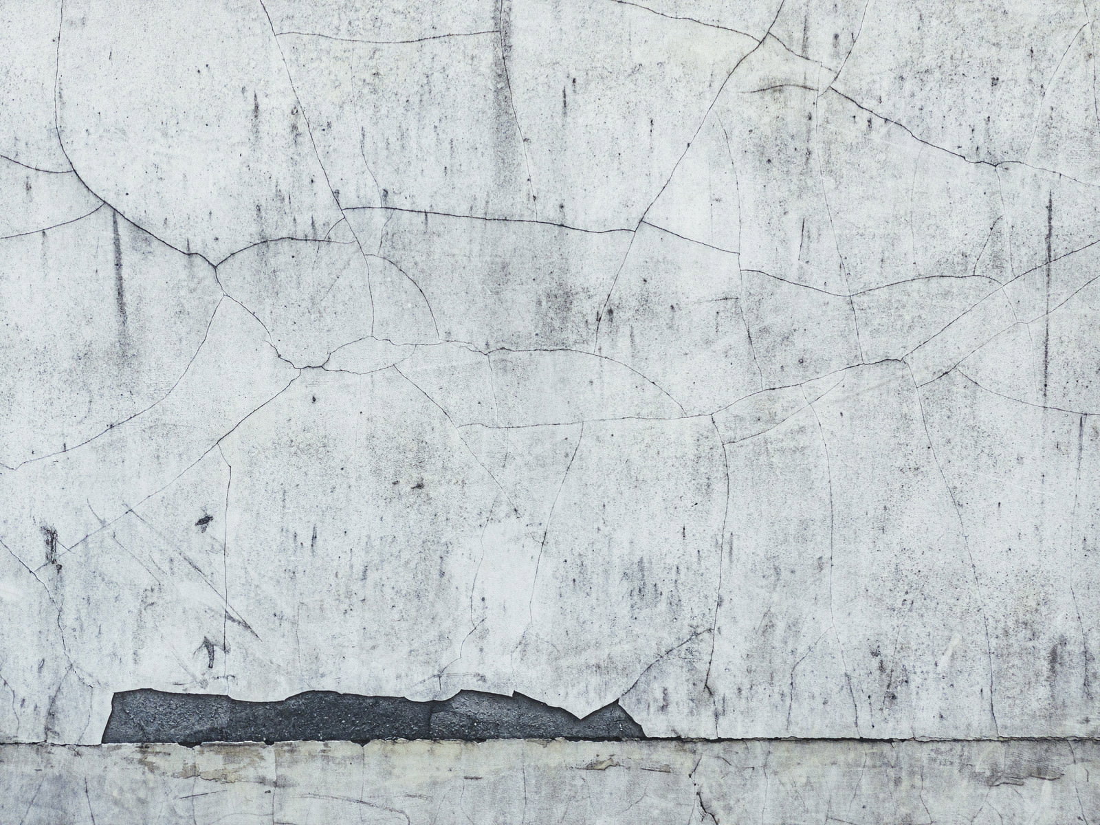 表面に大小のひび割れが入った老朽化したコンクリートの壁