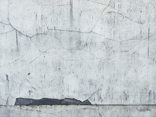 大小のひび割れが著しいコンクリート壁の劣化状態