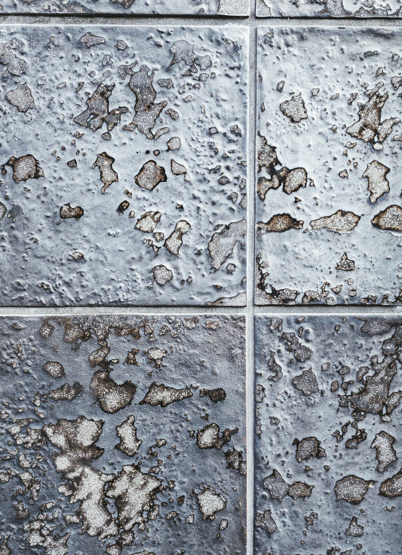 溶けたような凹凸模様が不規則に配置されたグレーの壁面