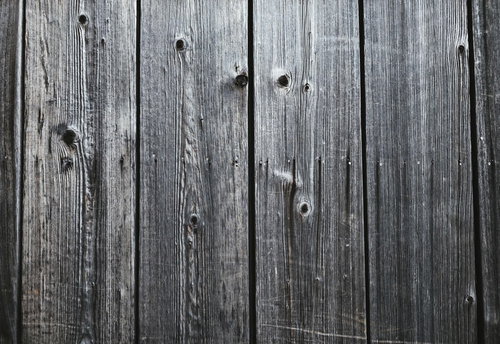 古びた灰色の板材に残る節穴と釘跡