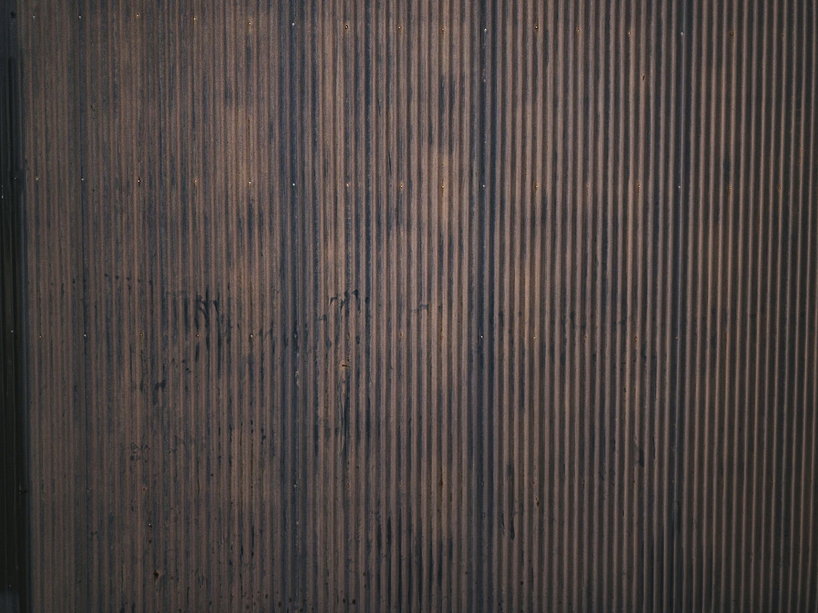 茶色に錆びたトタンの壁面に縦縞模様が入った金属テクスチャー