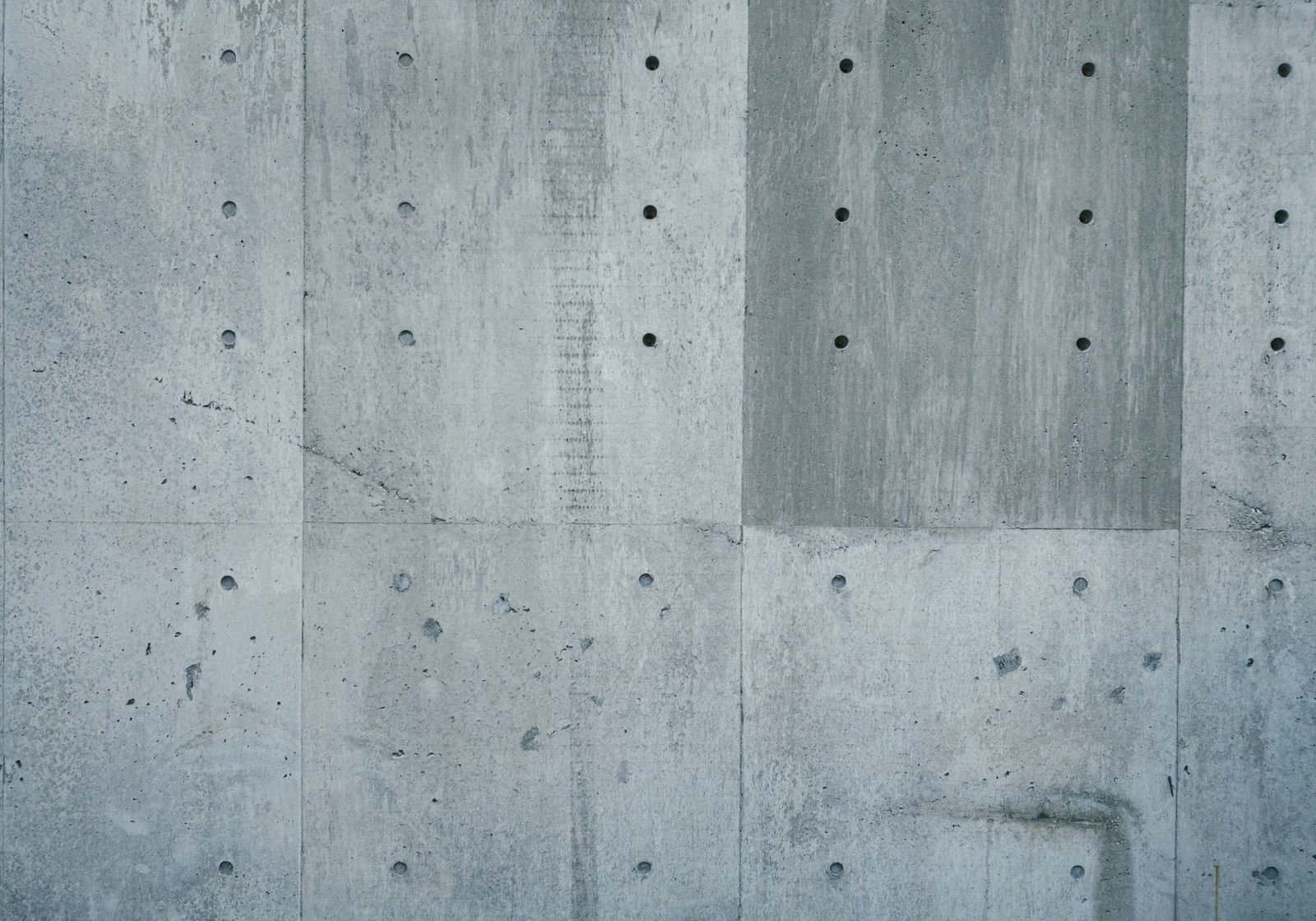 縦方向の板跡と小さな穴が規則的に配置された打ち放しコンクリートの表面