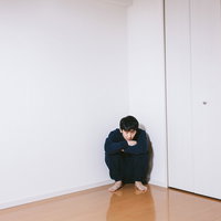 コーナーで膝を抱えて座り込むニート男性の心理状態の写真