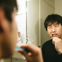 歯磨き中にえずく男性の朝の支度とオーラルケアの写真