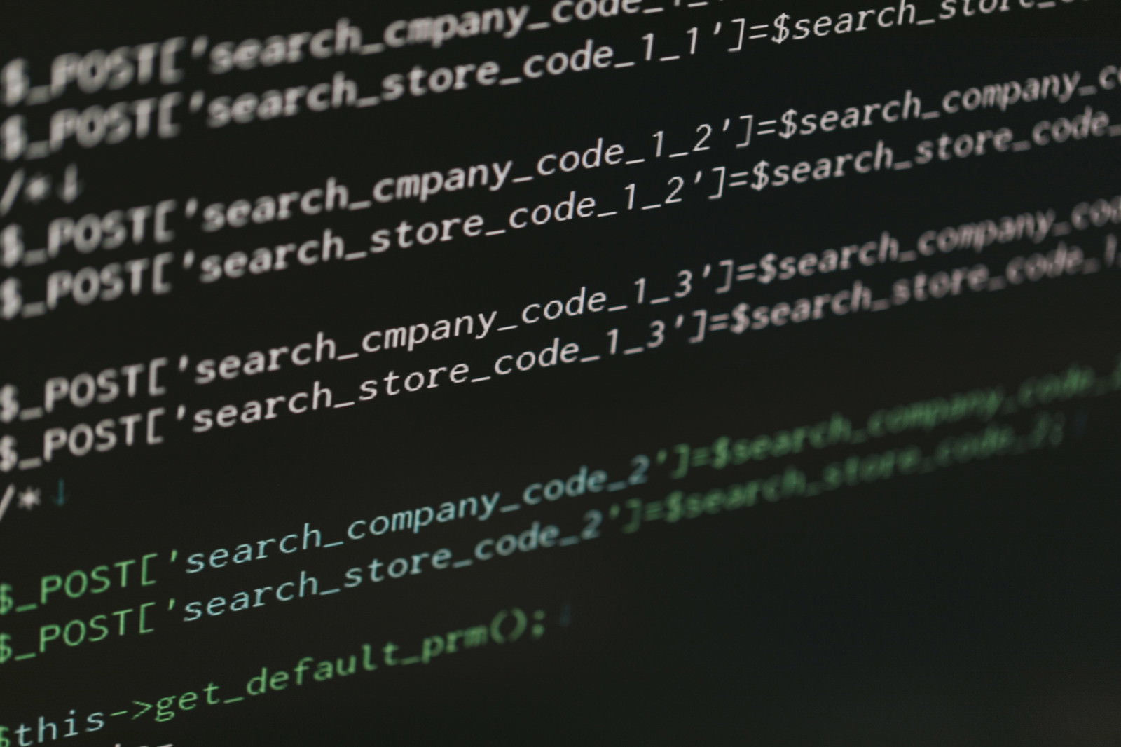 PHPコードをモニターで指差し確認するエンジニア