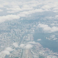 雲の切れ目から見える東京の高層ビル群と湾岸エリアの写真