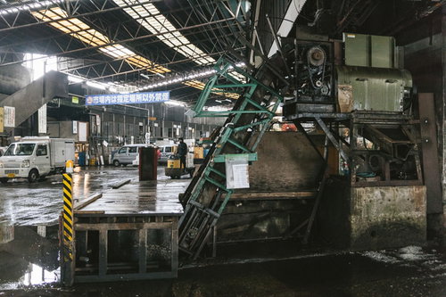 築地市場の卸売場で稼働する緑色の老朽化した荷上げ機械