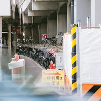 駅前の駐輪場に並ぶ赤やピンク色のシェアサイクルと黒紺の自転車群の写真