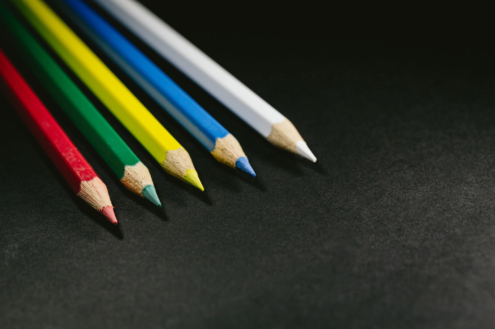 黒い背景に斜めに並ぶ5本の色鉛筆
