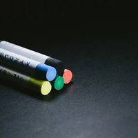 黒い机の上に並んだ5色のクレヨンの写真