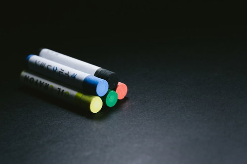 黒い机の上に並んだ5色のクレヨン