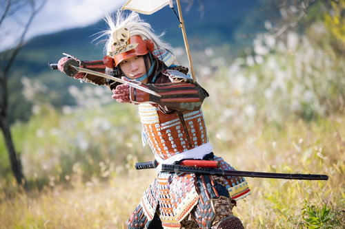 白髪の武将が太刀を構える赤い当世具足と骸骨兜の戦国武士姿