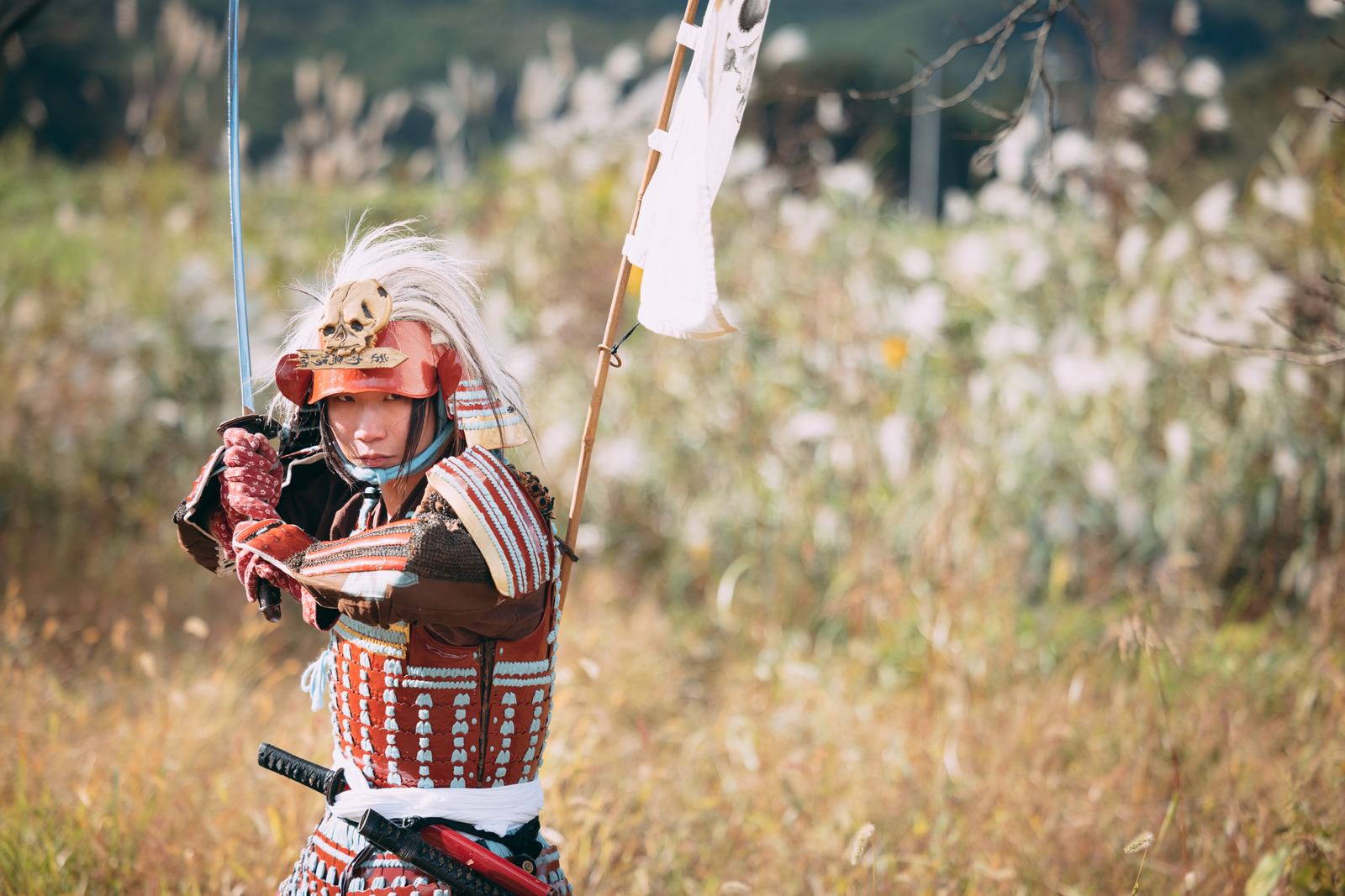 当世具足を着用し日本刀を構える侍が草原で戦闘態勢を取っている［モデル：まーこ］