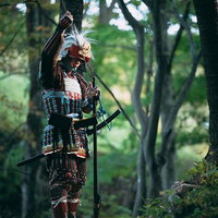 当世具足を身にまとい火縄銃に火薬を詰める武将の写真