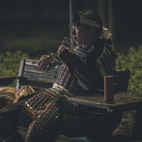 夜の公園ベンチで日本酒に舌鼓をうつ当世具足姿の侍の写真