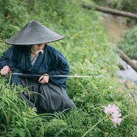 水辺に身を潜める網代笠を被った侍が刀を構えるの写真