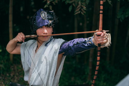 紫の鉢巻きで弓を引く野盗、集中した表情で弓矢を構える和装の男性