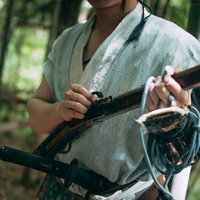 竹林の中で火縄銃に着火準備をする野盗の男性の写真