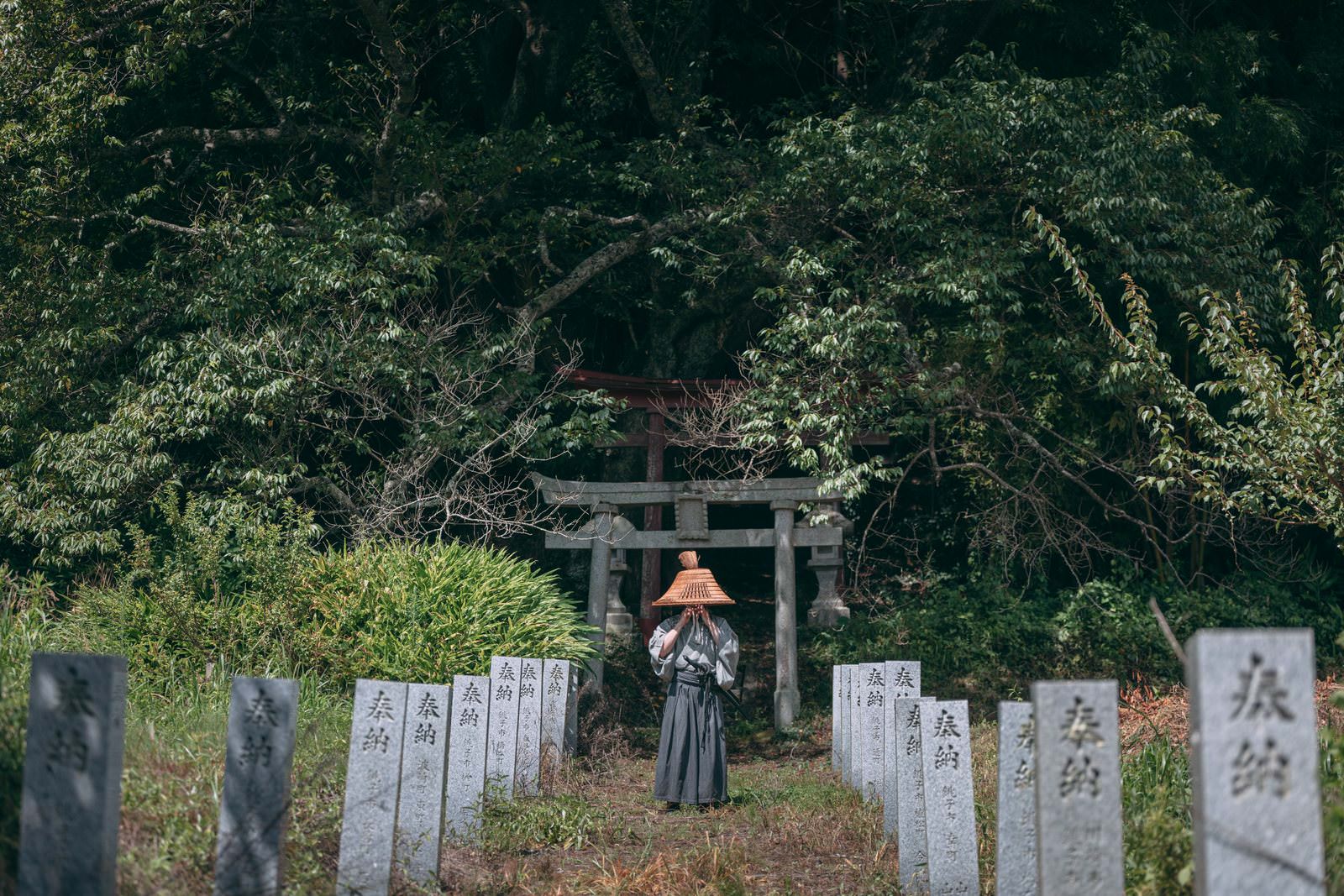 網代笠を被った袴姿の侍が鳥居の前に立つ［モデル：まーこ］