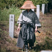 網代笠を被り奉納石柱の間を闊歩する武士の姿の写真