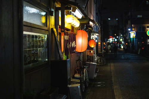 提灯が灯る路地裏の居酒屋の夜景と自転車のある日本の夜