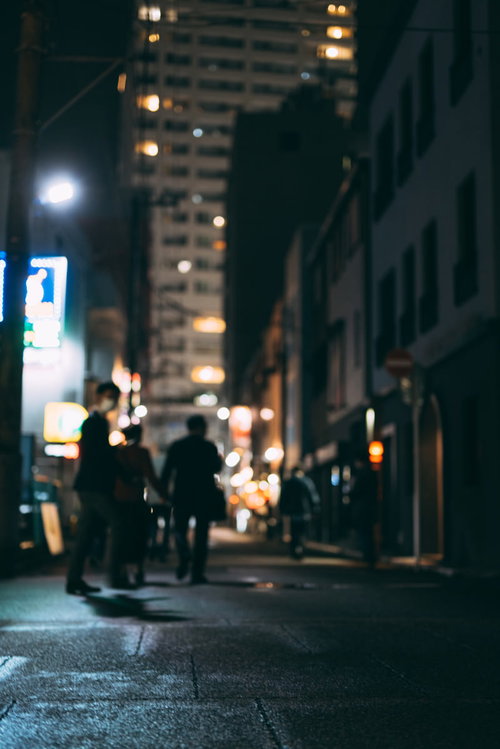 飲み明かして帰路に就く会社員の後ろ姿、夜の繁華街の路地裏