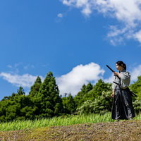 青い空と草原で刀を構える袴姿の侍の抜刀の写真
