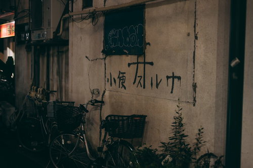 野毛の外壁に書かれた小便スルナの落書きと放置自転車