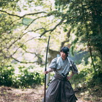 長巻の刃を見つめる侍の構え - 緑豊かな自然での武術鍛錬の写真