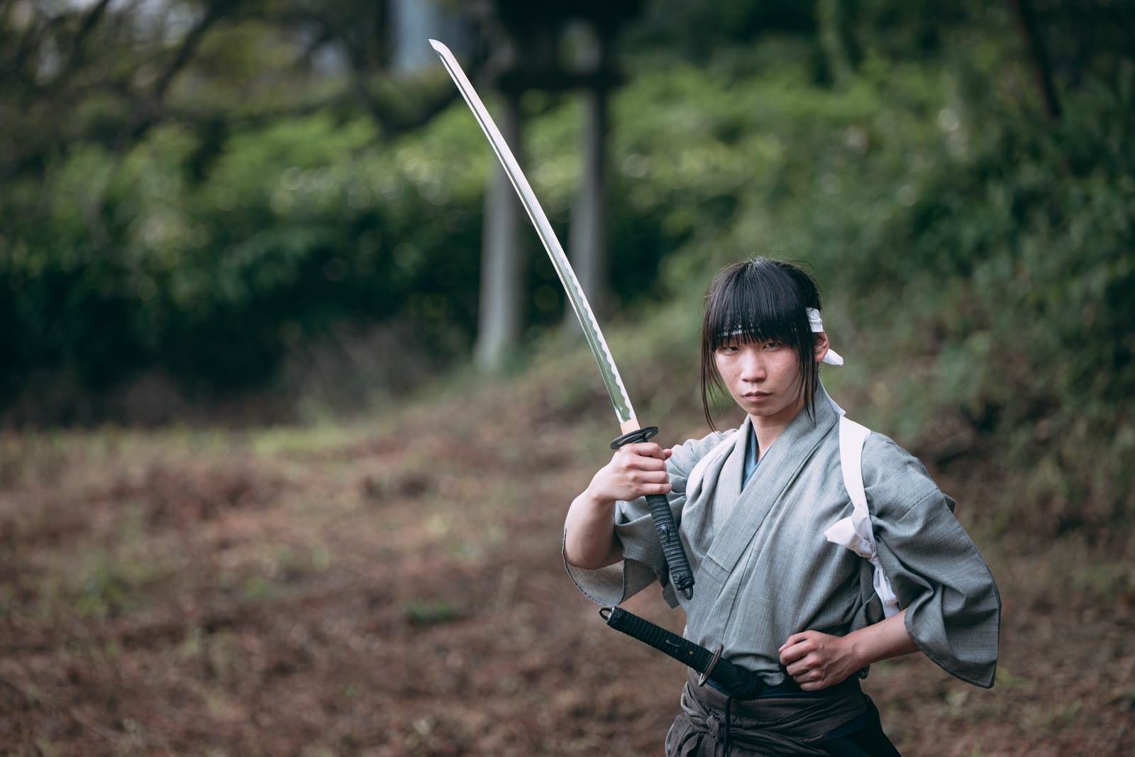 袴を着た侍が左手を腰に当て、右手で日本刀を構えている［モデル：まーこ］