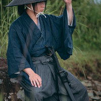 岩に腰かけて一休みする網代笠を被った袴姿の侍の写真